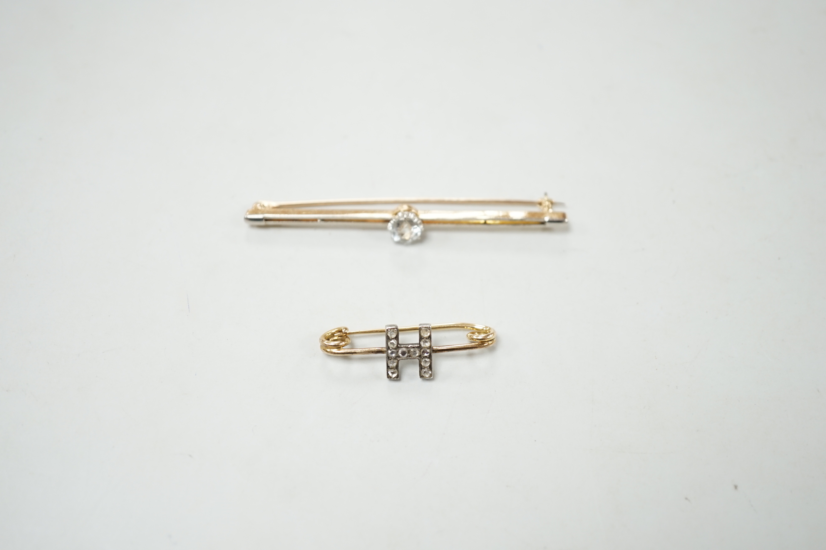 An early 20th century yellow metal and rose cut diamond set initial 'H' brooch, 32mm and a yellow metal and aquamarine set bar brooch, gross weight 7.1 grams.
